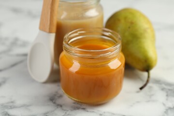 Tasty baby food in jar on white marble table, closeup