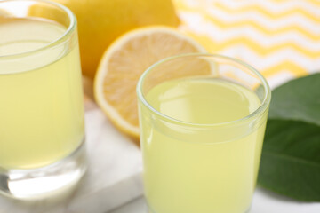 Shot glasses with tasty limoncello liqueur on table, closeup. Space for text
