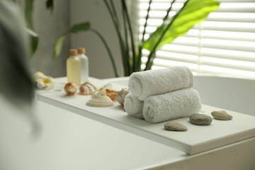 Fototapeta na wymiar Bath tray with spa products and towels on tub in bathroom