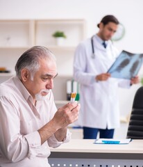 Young male doctor and old patient in antismoking concept