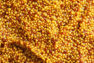 Whole grain mustard as background, top view