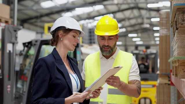 Female warehouse director talking with production manager, discussing new order, preparing products for shipmennt, delivery, checking stock in warehouse.