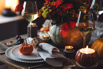 Atmospheric autumn elegant beautiful table setting with pumpkins for a wedding or thanksgiving family celebration. Fall decoration countryside rustic style, cozy home atmosphere , candles, wine