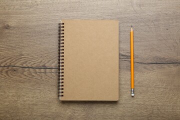 Notebook and pencil on wooden table, top view