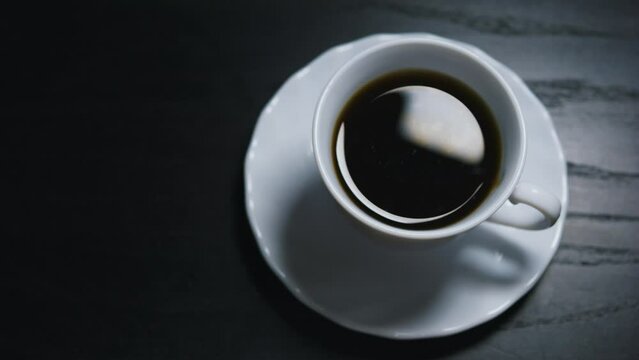 Cup of black coffee on black wooden table. Close up. Top view.