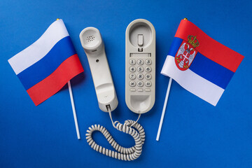 Old telephone and two flags on a blue background, concept on the theme of telephone conversations...