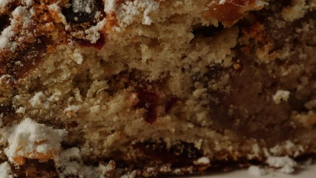 German Stollen bakery dessert close-up. Bun with spices, raisins, nuts and candied fruits and powdered sugar on top. Christmas desserts. Bakehouse