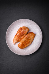 Delicious fresh grilled chicken fillet with spices and herbs on a dark concrete background