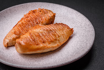 Delicious fresh grilled chicken fillet with spices and herbs on a dark concrete background