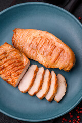 Delicious fresh grilled chicken fillet with spices and herbs on a dark concrete background