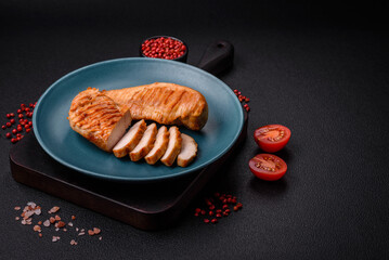 Delicious fresh grilled chicken fillet with spices and herbs on a dark concrete background