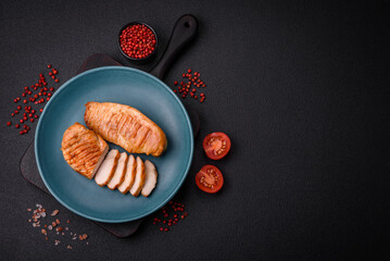 Delicious fresh grilled chicken fillet with spices and herbs on a dark concrete background