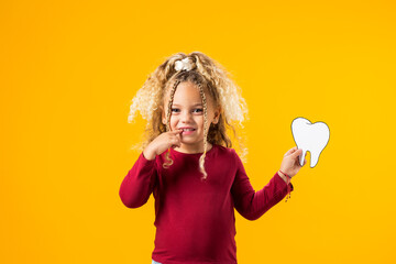 A Girl Delightfully Holding a Papercraft Tooth Symbolizing Oral Wellness