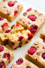 Blondies with raspberries and pecan nuts. White background. Back view