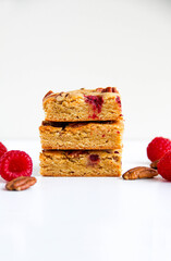Blondies with raspberries and pecan nuts. White background. Back view