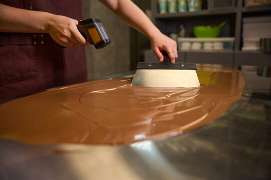 Experienced confectioner busy with tempering chocolate on kitchen countertop