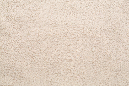 Beige cuddle teddy bear fabric as background, top view