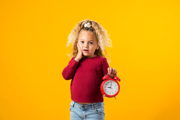 Young girl holding an alarm clock, symbolizing time management, education, school, and the urgency of deadlines and study.