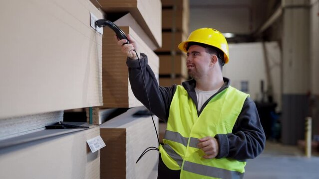 Video of young man with Down syndrome working in warehouse. Concept of workers with disabilities, support in workplace.