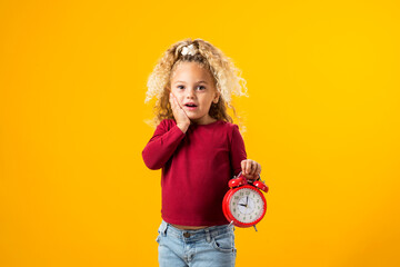 Young girl holding an alarm clock, symbolizing time management, education, school, and the urgency...