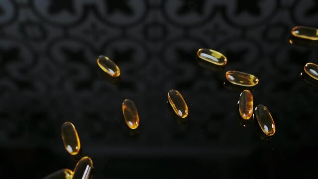 Handful of yellow capsules with vitamin D3 scatter randomly on a black reflective surface. The concept of taking vitamins, fish oil, bio supplements for health, place for text.
