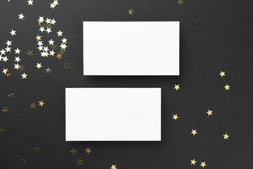 Blank business cards and confetti on black background, top view. Mockup for design