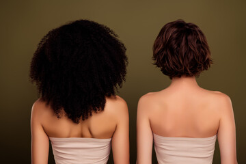 Naklejka premium Rear view of two different ladies with curly american hairstyle vs bob brown haircut isolated on khaki color background