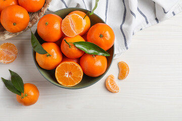 Delicious tangerines with green leaves on white wooden table, flat lay. Space for text