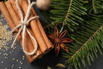 Different spices and fir branches on gray table, flat lay
