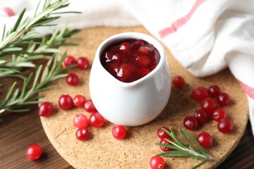 Cranberry sauce, fresh berries and rosemary on wooden table, closeup
