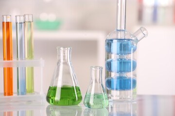 Laboratory analysis. Different glassware with liquids on white table against blurred background