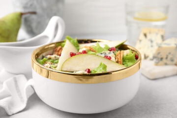 Delicious pear salad in bowl on light table, closeup