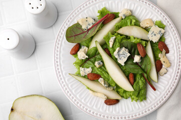 Delicious pear salad on white tiled table, flat lay