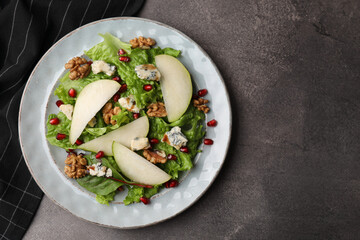 Delicious pear salad on dark textured table, top view. Space for text