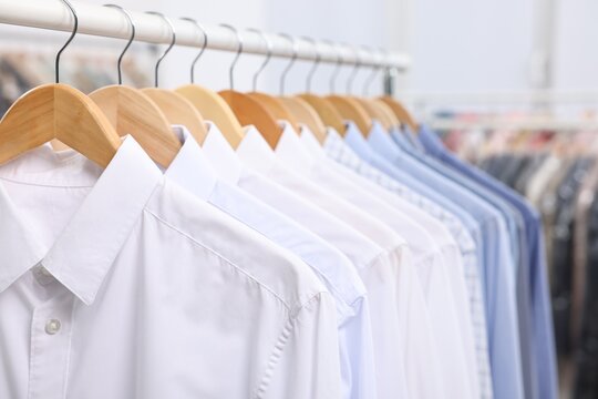 Dry-cleaning service. Many different clothes hanging on rack indoors, closeup