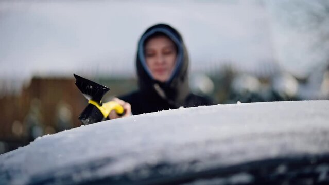Woman Cleaning Car from Snow in Winter. Driver Brushing Snow off Top of the Car with a Brusher Scraper	