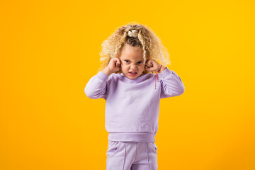 Child girl covering her ears and tightly closed eyes. Unwilling to listen, to hear something. Negative emotions concept