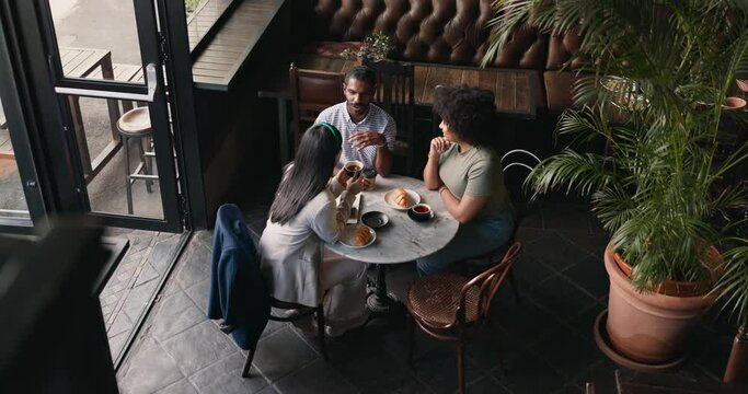 Friends, group and talking in coffee shop for communication catch up or university reunion, gossip or above. Man, woman and chat in cafe together as consumer for bonding lunch, diversity or social