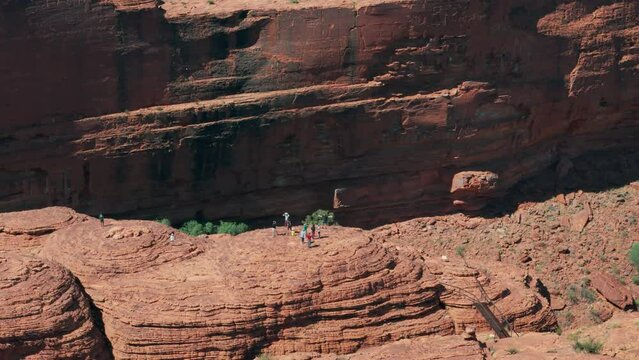Aerial orbit footage of tourists standing on top of Kings Canyon Australia