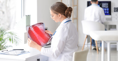 Female doctor studying x-ray image of lungs in clinic - obrazy, fototapety, plakaty
