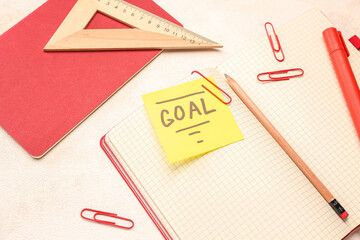 Sticky note with word GOAL and stationery on light background, closeup