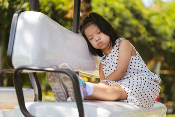 Young Girl aged 6 years old Daydreaming in Park, Thoughtful Kid rests her cheek on backrest cushion...