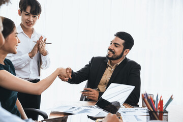 Diverse coworkers celebrate success with handshake and teamwork in corporate workplace....