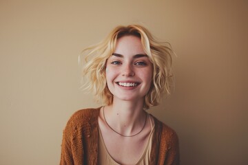 Smiling pretty gen z blonde young woman, cute happy 20s european student girl with short blond hair and white dental smile looking at camera standing isolated on beige background, portrait - obrazy, fototapety, plakaty