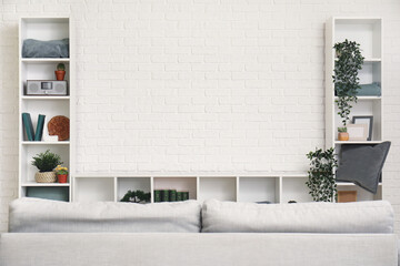 TV stand with books and plants near white brick wall in living room