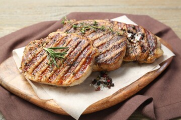 Delicious grilled pork steaks with herbs and spices on table, closeup