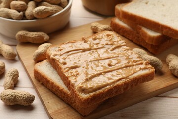Delicious toasts with peanut butter and nuts on light wooden table, closeup