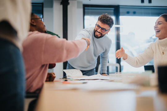 Multiracial business team celebrating a successful finished project, smiling and overjoyed with their achievements and positive outcomes.