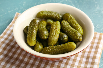 Bowl with tasty pickled cucumbers on blue background