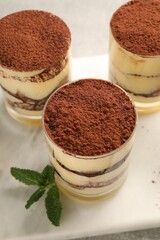 Delicious tiramisu in glasses and mint on table, above view